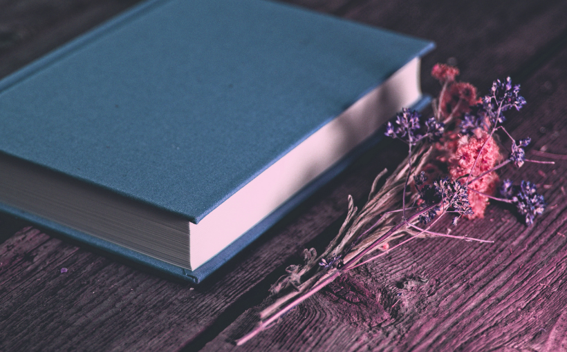 livro de capa dura azul com flor ao lado